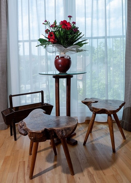 Zdjęcie pokoju z dwoma taboretami, stolikiem do kawy i stojakiem na czasopisma wykonanymi z drewna