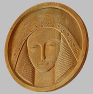 Płaskorzeźba głowy kobiecej wyrzeźbiona w drewnie zatytułowana Bogini Słońca